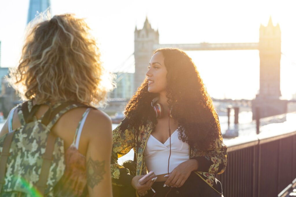 UK, London, two friends together in the city with Tower Bridge in background at sunset | SUPERPOBYT World
